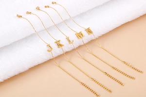 Detailed close-up of golden stainless steel bracelets with diamond-encrusted letter charms