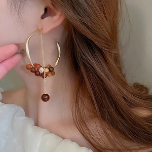 Detail of C-shaped twisted earrings with ebony beads and matte gold metal chain