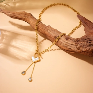 Gold-plated stainless steel heart necklace with fringe on driftwood under water ripples