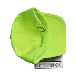 Neon green kids baseball cap on a digital scale showing a weight of 78.4 grams