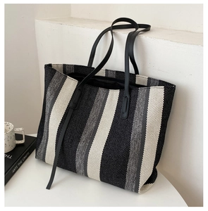 Detail of minimalist tote bag showing woven texture and black leather shoulder strap