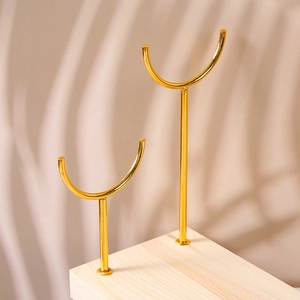 Detail of light luxury gold metal double-tier jewelry stand with natural wood base