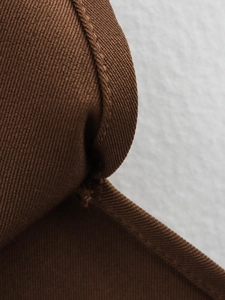 Macro view of dark brown twill fabric texture and fine stitching detail on padded top