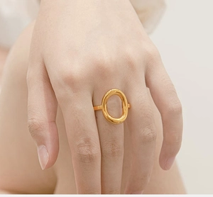 Detail of a minimalist gold hollow oval geometric ring worn on a finger for a chic look