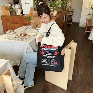 Detail of black canvas tote bag featuring vintage American style graphic print in a cafe