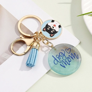 Close-up of a dog mom resin keychain with blue tassel and Shiba Inu charm on a plate