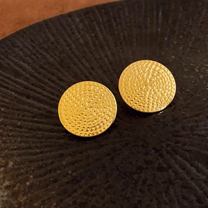 Primo piano di orecchini a lobo dorati rotondi con texture metallica a scaglie unica