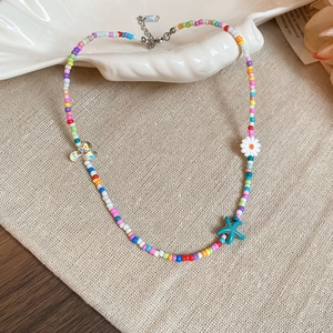 Detailed macro view of colorful beaded necklace with starfish charm and daisy pendant