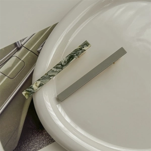 Detail view of marble green and matte grey acetate hair clips on a ceramic plate