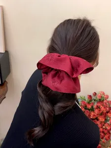 Close-up of wine red jacquard satin hair scrunchie with rose patterns on black braided hair