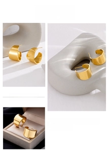 Macro detail of gold C-shape chunky hoop earrings with mirror polished finish