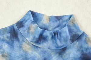 Detailed close-up of blue tie-dye mesh fabric on high collar dress with sheer texture