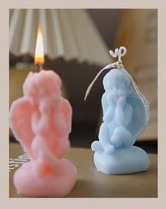 Detailed view of pink and blue angel-shaped candles with silk ribbon and wax texture
