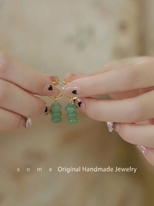 Detail of green aventurine beaded drop earrings with golden round clasps on hand