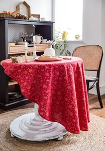 Detailed view of red Christmas tablecloth featuring golden snowflake and bell prints