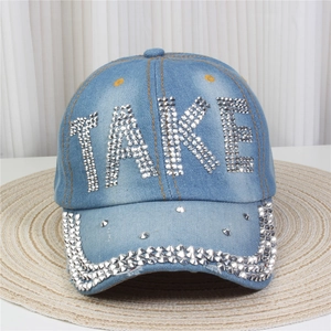 Gros plan du mot TAKE en strass argentés sur une casquette en denim bleu clair