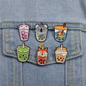 Close-up of six creative animal boba tea enamel pins on blue denim fabric background