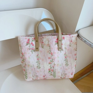 Detail of floral tote bag showing faux leather handles and sturdy brass rivets