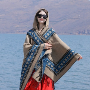 Détail du motif cœur et franges noires sur un poncho bohème beige à capuche