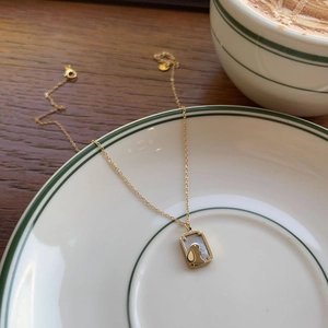 Elegant gold titanium rabbit necklace with white shell pendant on a stylish ceramic plate