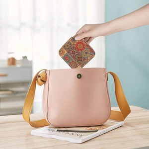 Detail of placing a pink leather shoulder bag and vintage floral wallet in a home setting