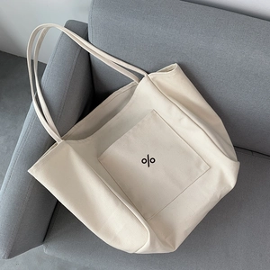 Detail of minimalist beige canvas tote bag with thick texture and front pocket on a sofa