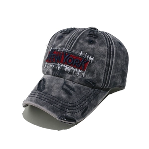 Macro detail of New York embroidery on distressed washed denim baseball cap with torn edges