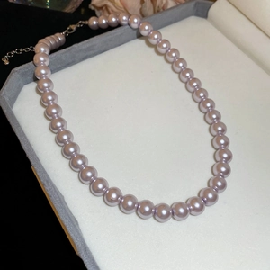 Macro shot of lavender pearl necklace with metallic clasp in a light grey jewelry box