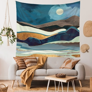 Modern abstract mountain tapestry featuring gold textures and a moon above a sofa