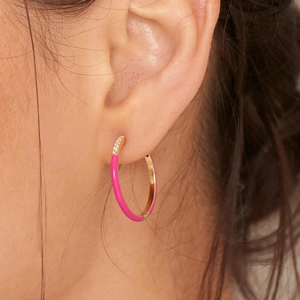 Pink enamel and gold plated hoop earrings with zircon stones worn by a model