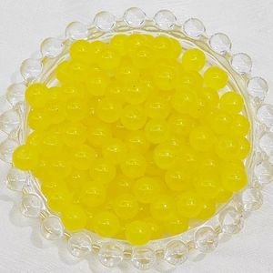 Macro view of translucent yellow glass beads in a clear tray for DIY jewelry making