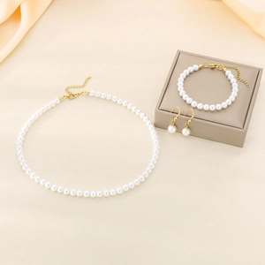 Elegant gold stainless steel jewelry set with white pearls on a silk background
