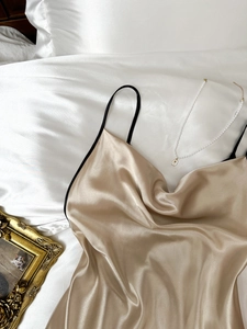 Détail de la chemise de nuit en satin champagne avec fines bretelles noires