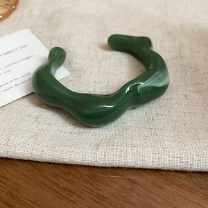 Close-up of deep green irregular wavy acrylic cuff bracelet with marble texture