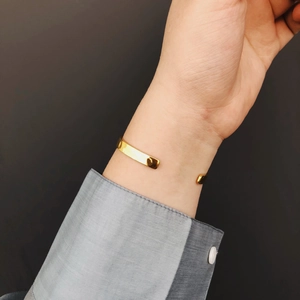 Close-up of golden lunar surface textured open cuff bracelet worn on model wrist