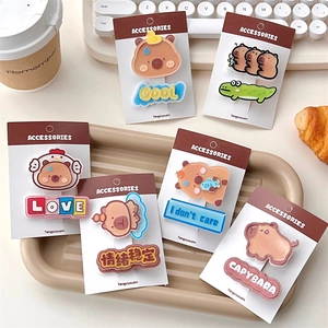 Close-up of six Capybara cartoon acrylic hair clips in warm brown and khaki tones