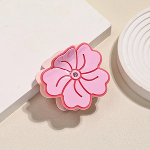 Pink acetate flower hair claw with rhinestone detail on a minimalist cream background
