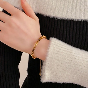 Close-up of golden tiger eye stone bracelet on wrist with elegant knit sweater detail