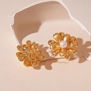 Détail de boucle d'oreille fleur dorée à clip avec perle blanche et fermoir