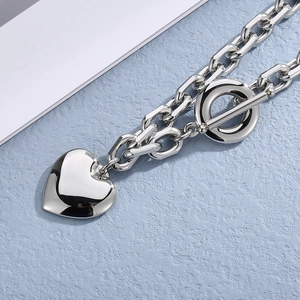 Detail of silver heart pendant necklace with T-bar toggle clasp on blue texture