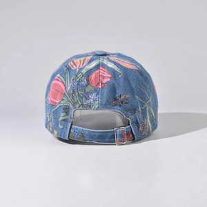 Detail of denim baseball cap showing floral embroidery and adjustable metal buckle strap