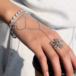 Detail of silver finger bracelet with green floral ring and shimmering zircon stones