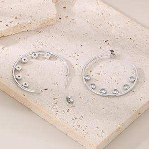 Macro detail of silver stainless steel C-shaped hoop earrings with clear zircon stones