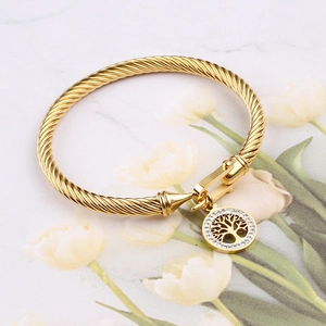 Macro detail of gold tree of life charm with cubic zirconia on cable twist bangle