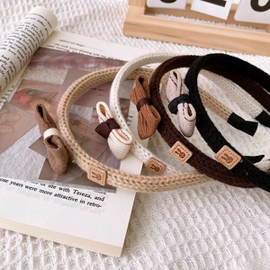 Close-up of knitted bow headbands in khaki, beige, and brown with rabbit tags