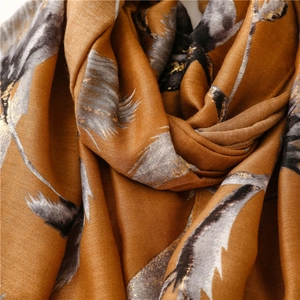 Macro detail of mustard yellow linen-feel scarf featuring elegant gold foil feather patterns