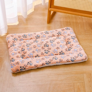 Close-up of soft orange-pink plush pet mat with paw prints on warm wooden floor