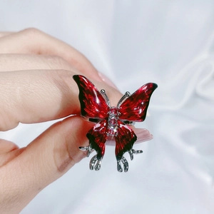 Detailed view of red and black enamel butterfly ring worn on finger with sparkling crystals