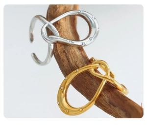 Detail of twisted horseshoe rings in gold and silver finish on a wooden branch