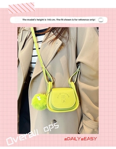 Detail of mini lime green crossbody bag with embossed logo and fuzzy pompom charm